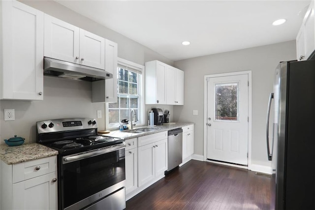 kitchen featuring white cabinets, dark wood finished floors, appliances with stainless steel finishes, under cabinet range hood, and a sink