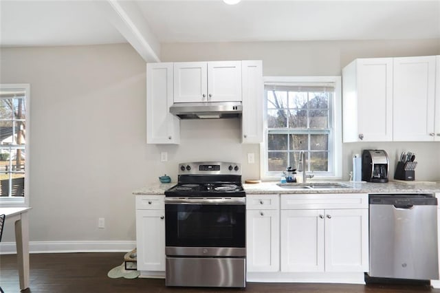 kitchen featuring light stone counters, stainless steel appliances, white cabinetry, a sink, and under cabinet range hood