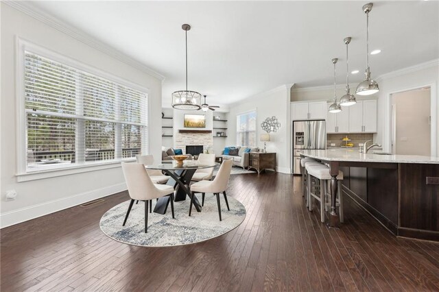 dining area with dark wood-type flooring, ornamental molding, a chandelier, and sink