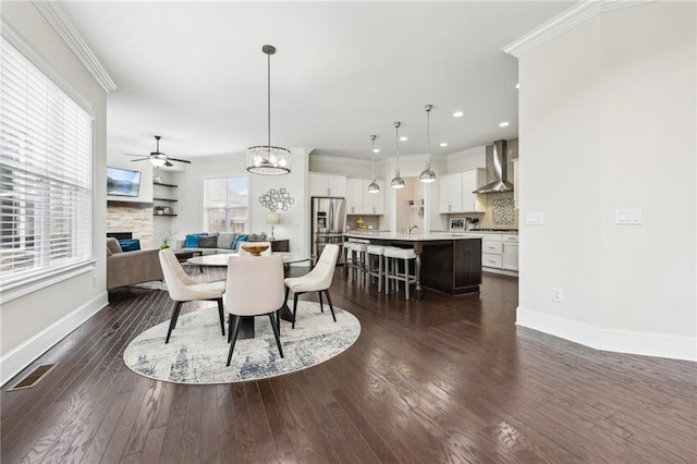 dining space with dark hardwood / wood-style flooring, sink, crown molding, and ceiling fan with notable chandelier