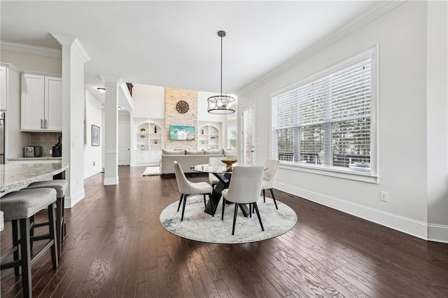 dining space featuring crown molding, dark wood-type flooring, decorative columns, and built in features