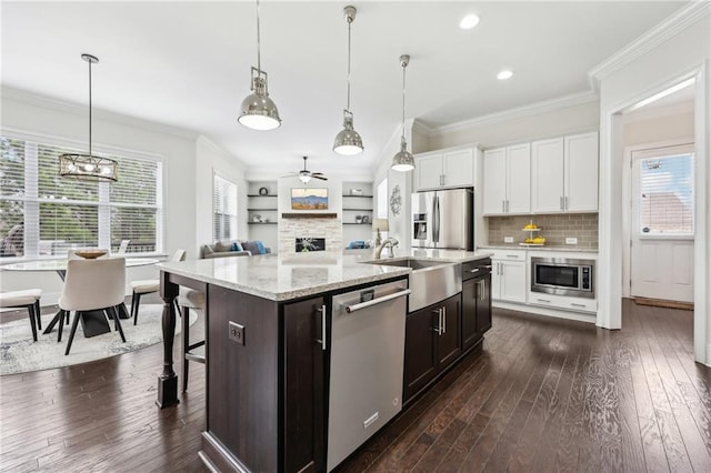 kitchen featuring appliances with stainless steel finishes, a breakfast bar, pendant lighting, white cabinets, and a center island with sink