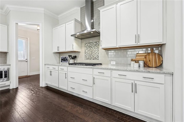 kitchen with white cabinetry, wall chimney exhaust hood, light stone countertops, ornamental molding, and stainless steel gas stovetop