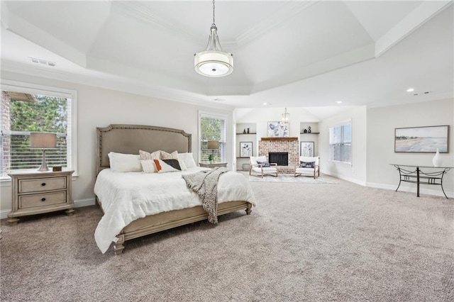 carpeted bedroom featuring a tray ceiling, a fireplace, and ornamental molding