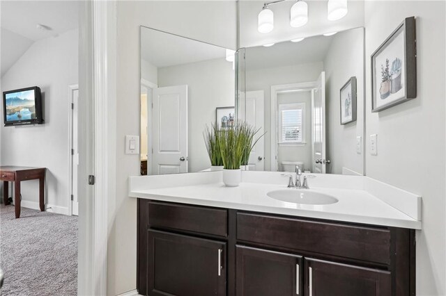 bathroom featuring lofted ceiling, vanity, and toilet