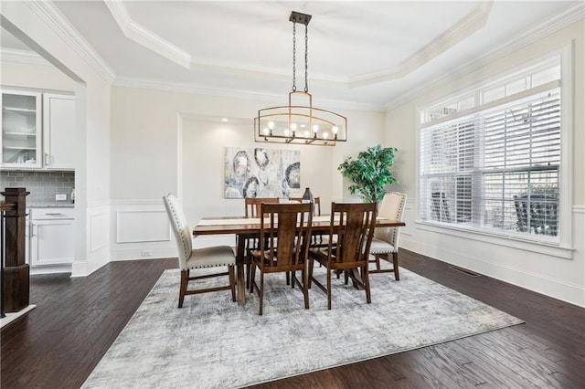 dining space featuring crown molding, dark wood-type flooring, and a raised ceiling