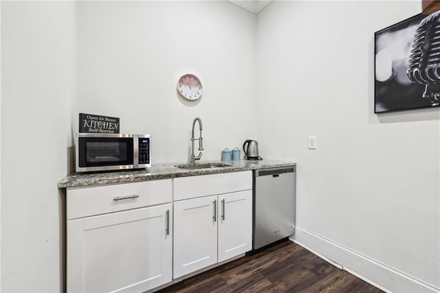 bar with sink, white cabinetry, light stone counters, dark hardwood / wood-style flooring, and stainless steel appliances