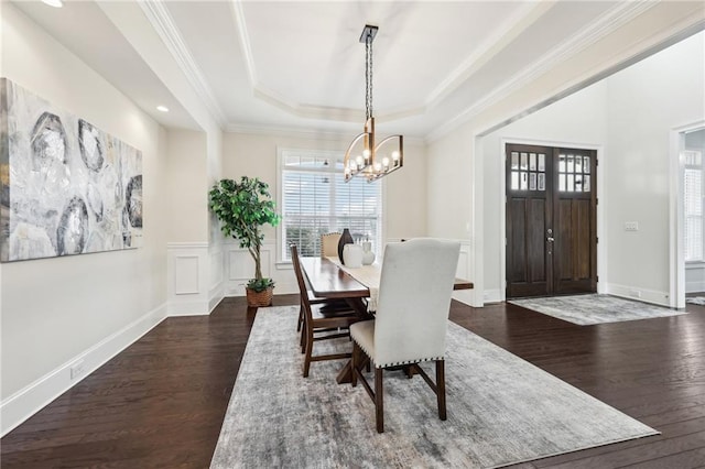 dining area with ornamental molding, dark hardwood / wood-style floors, a raised ceiling, and a notable chandelier