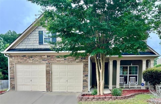 obstructed view of property featuring a garage, covered porch, driveway, and stone siding