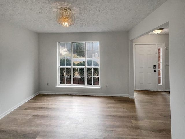 interior space featuring a textured ceiling, wood finished floors, and baseboards