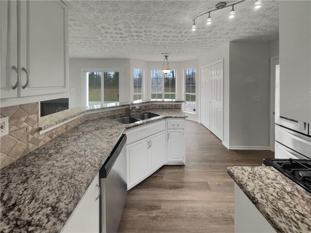 kitchen featuring stone counters, dark wood finished floors, a sink, a textured ceiling, and dishwasher