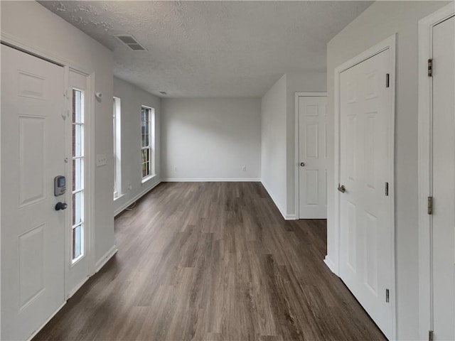 entryway featuring visible vents, a textured ceiling, baseboards, and dark wood-type flooring