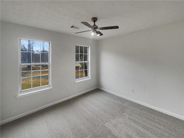 unfurnished room with a textured ceiling, carpet floors, visible vents, and a healthy amount of sunlight