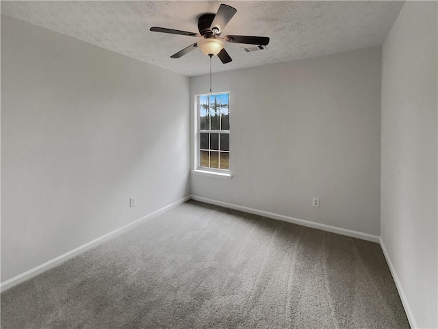 carpeted spare room featuring ceiling fan, visible vents, baseboards, and a textured ceiling