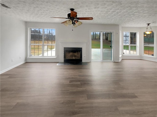 unfurnished living room featuring a textured ceiling, wood finished floors, and a wealth of natural light