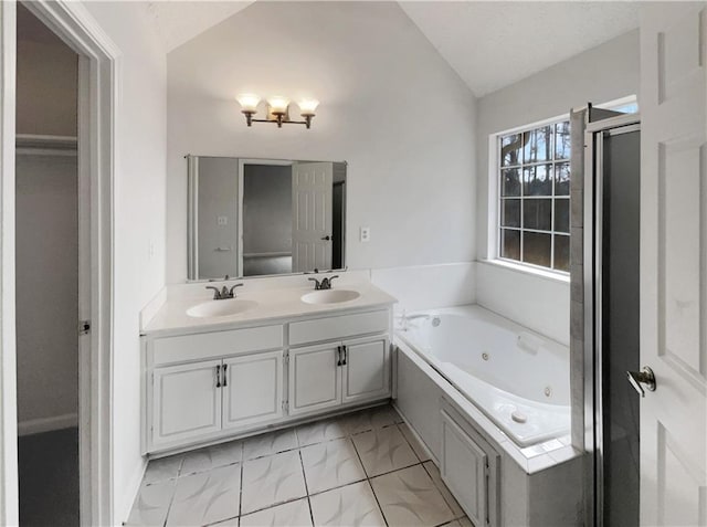 bathroom featuring vaulted ceiling, double vanity, a tub with jets, and a sink