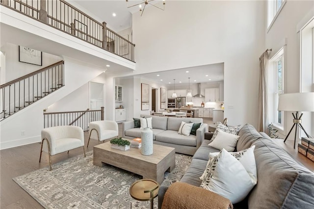 living room with stairway, baseboards, recessed lighting, a towering ceiling, and wood finished floors