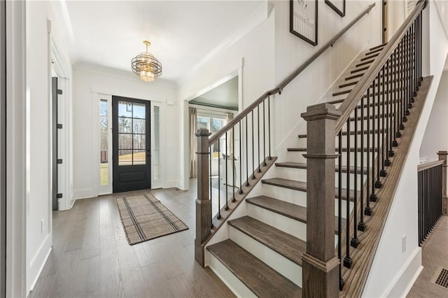 foyer entrance with baseboards, ornamental molding, and stairs