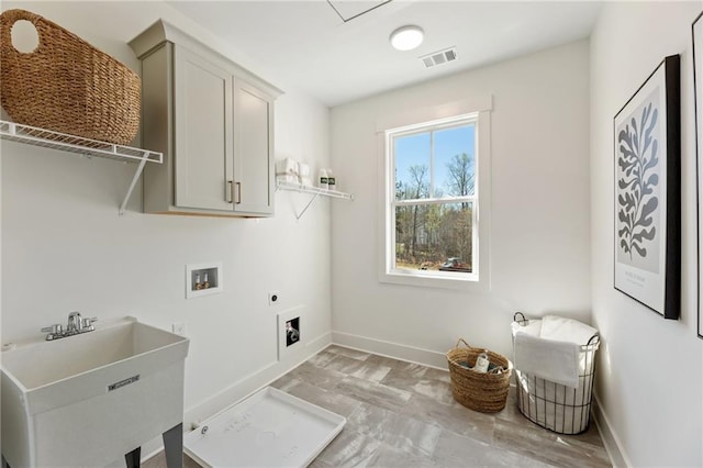 clothes washing area featuring visible vents, baseboards, cabinet space, and a sink
