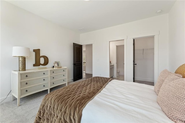 carpeted bedroom featuring ensuite bathroom, a walk in closet, a closet, and baseboards