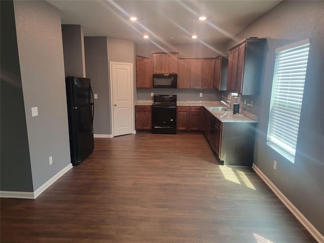 kitchen featuring black appliances, dark hardwood / wood-style floors, light stone countertops, and sink