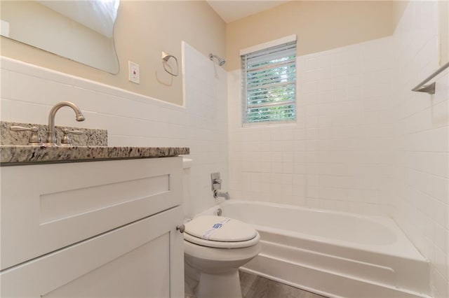 bathroom featuring toilet, bathing tub / shower combination, vanity, wood finished floors, and tile walls