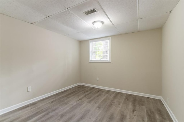 unfurnished room with a drop ceiling, wood finished floors, and baseboards