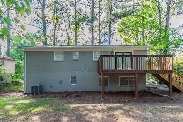 rear view of property featuring a deck, central AC unit, stairs, brick siding, and a carport