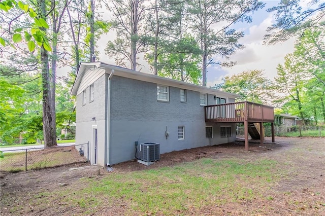 back of property with a wooden deck, central air condition unit, fence, stairway, and brick siding