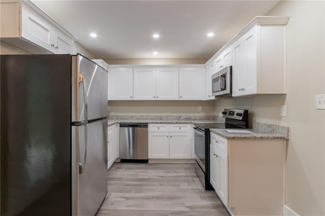 kitchen with appliances with stainless steel finishes, light wood finished floors, white cabinets, recessed lighting, and light stone countertops