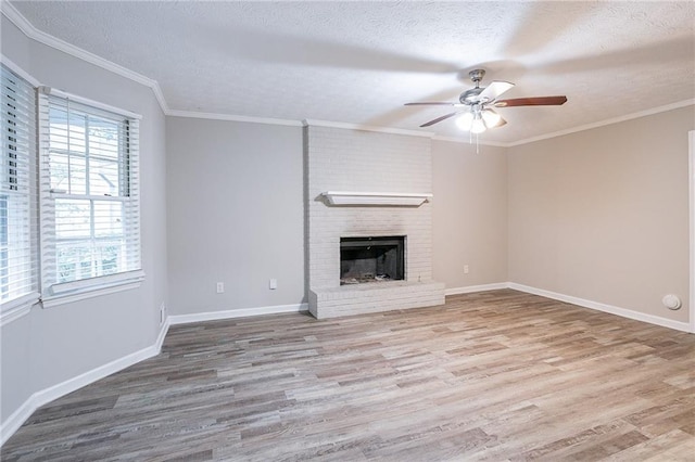 unfurnished living room with ceiling fan, hardwood / wood-style floors, a fireplace, ornamental molding, and a textured ceiling