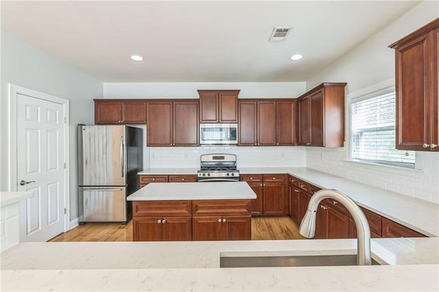 kitchen with appliances with stainless steel finishes, light wood-style floors, visible vents, and a sink