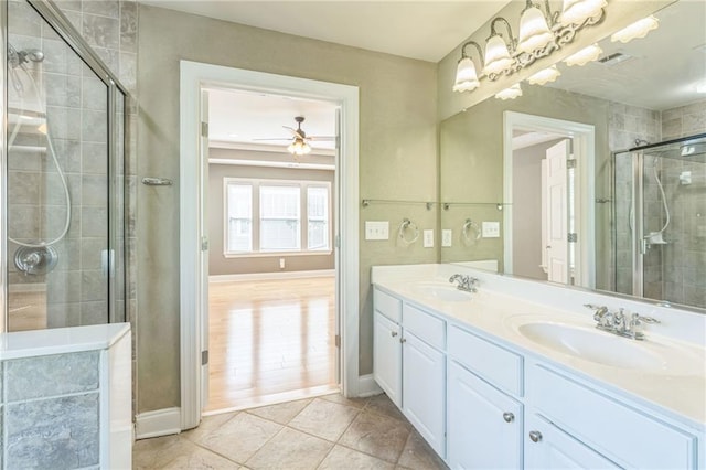 bathroom with a tile shower, tile patterned flooring, double vanity, a sink, and ceiling fan