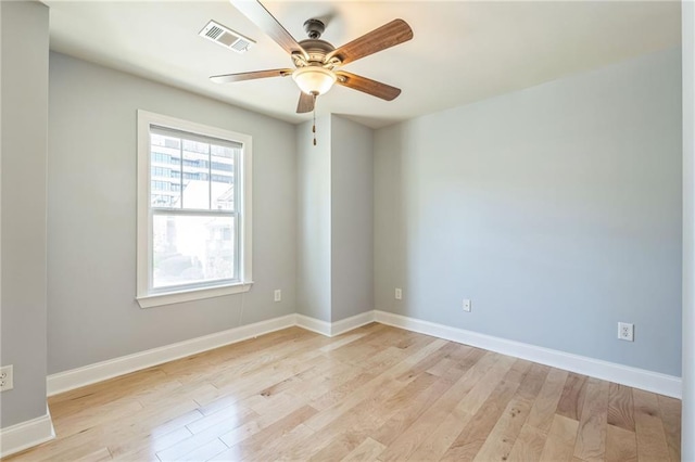 spare room with light wood-style floors, visible vents, a ceiling fan, and baseboards