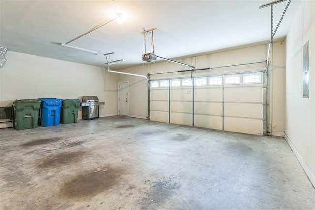 garage with a garage door opener, electric panel, and baseboards