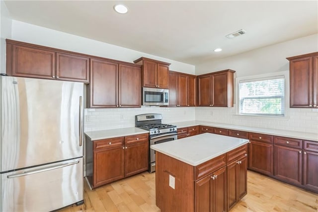kitchen featuring light wood-type flooring, stainless steel appliances, light countertops, and visible vents
