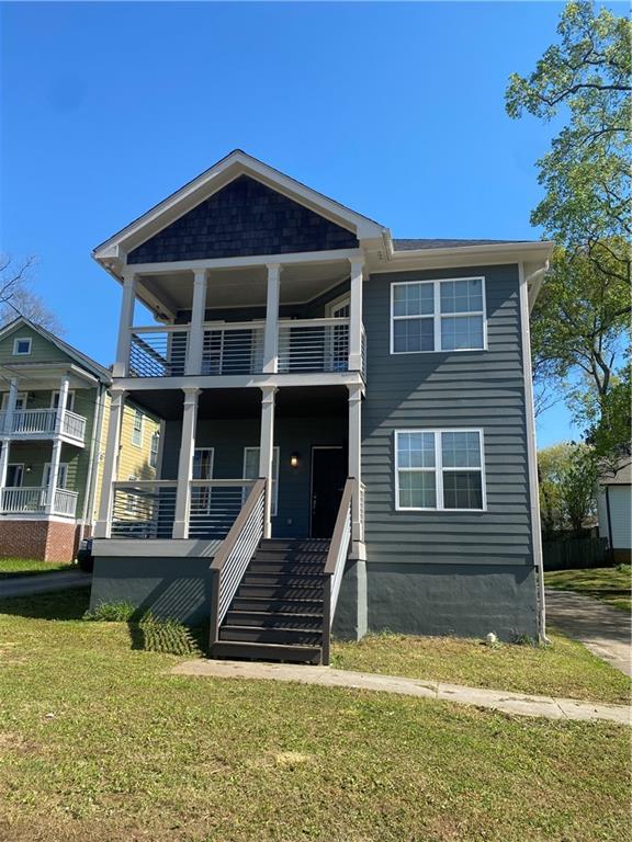 view of front facade featuring a balcony, a front lawn, and covered porch