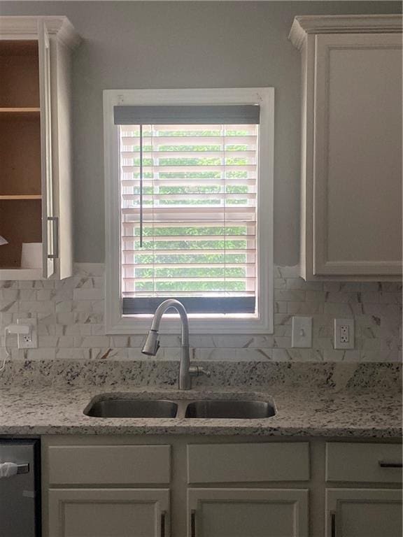 kitchen with white cabinetry, dishwasher, sink, and light stone countertops