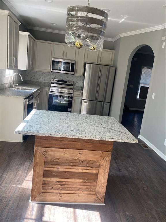 kitchen with sink, decorative backsplash, a kitchen island, dark hardwood / wood-style flooring, and stainless steel appliances