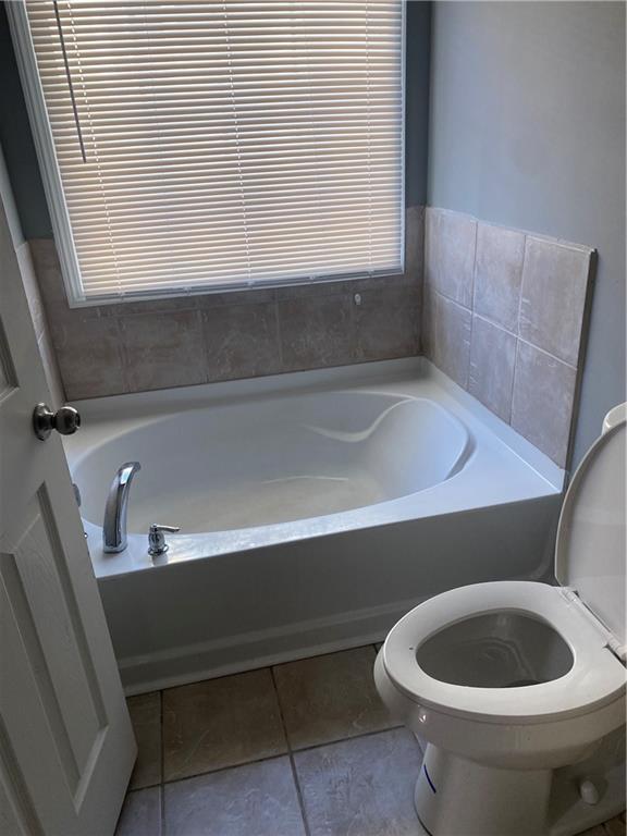 bathroom with tile patterned floors, a bathing tub, and toilet