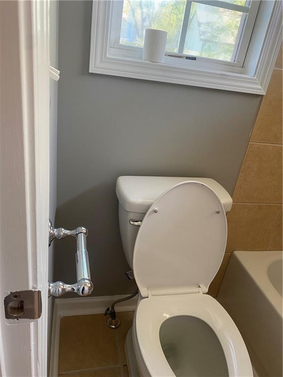 bathroom featuring tile patterned flooring, toilet, and a tub