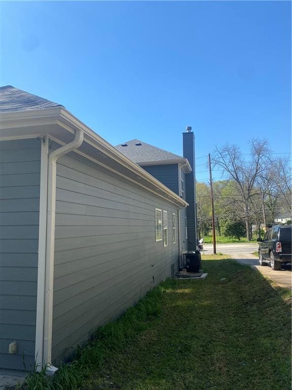 view of side of home with central AC and a lawn