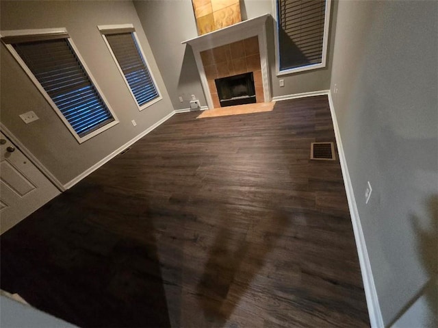 unfurnished living room featuring dark wood-type flooring and a tile fireplace