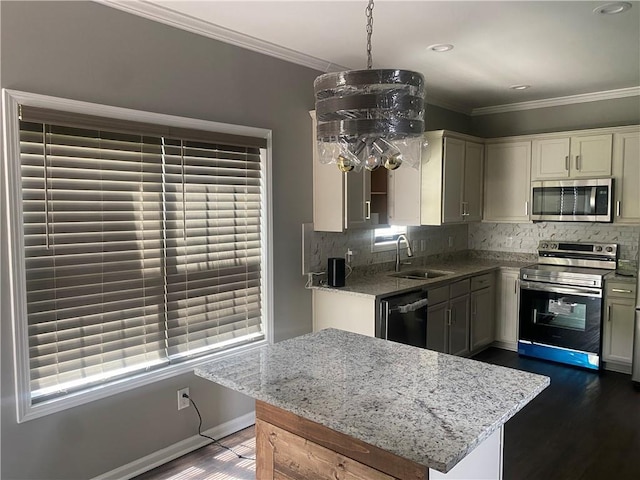 kitchen featuring sink, dark hardwood / wood-style flooring, crown molding, pendant lighting, and appliances with stainless steel finishes