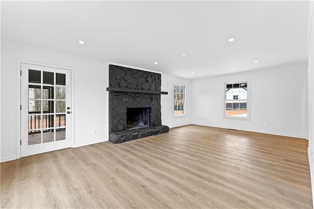 unfurnished living room with baseboards, ornamental molding, light wood-style floors, a fireplace, and recessed lighting