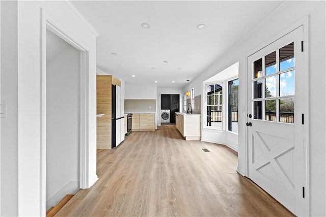 kitchen with recessed lighting, ornamental molding, freestanding refrigerator, light wood finished floors, and washer / dryer