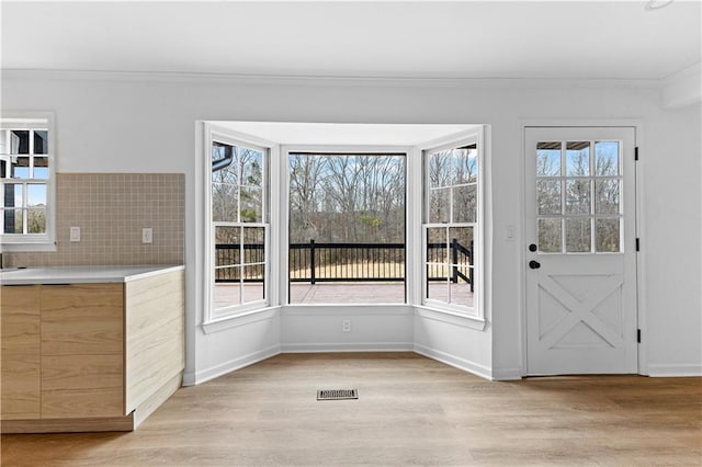 unfurnished dining area featuring a wealth of natural light, light wood-style flooring, and crown molding