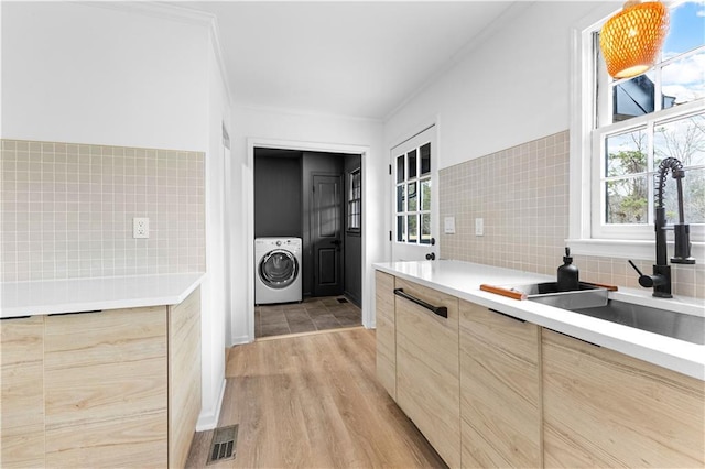 kitchen featuring washer / clothes dryer, light brown cabinets, a sink, and modern cabinets