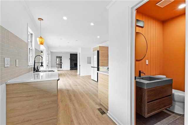 kitchen with light wood-style floors, freestanding refrigerator, a sink, and a high end fireplace