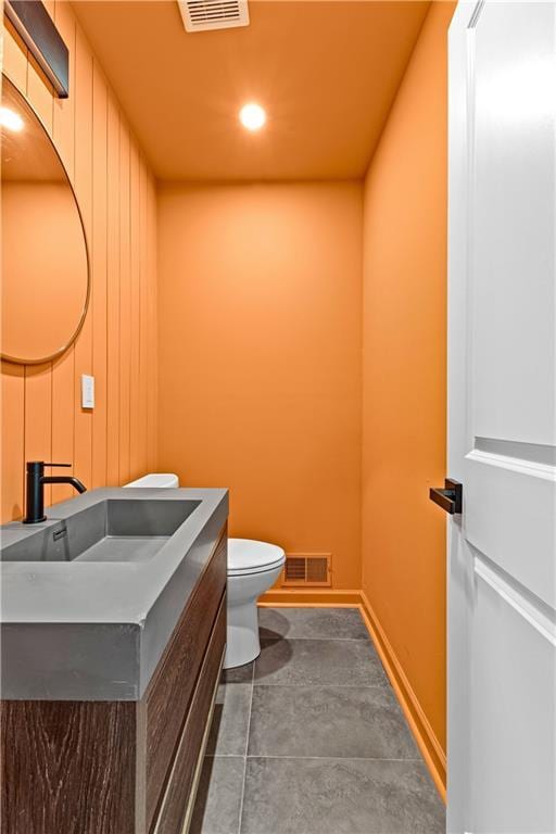 half bath with toilet, baseboards, visible vents, and vanity